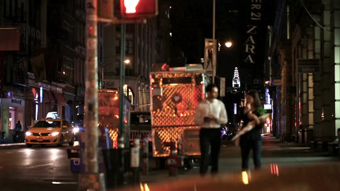 couple walking on Broadway on summer night in Manhattan with Chrysler Building in background in NYC