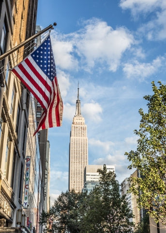 American flag and Empire State Building on beautiful colorful sunny summer blue sky day in Manhattan NYC