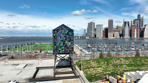 aerial circling Tom Fruin colorful Watertower water tank on Dumbo Brooklyn rooftop Manhattan skyline New York City