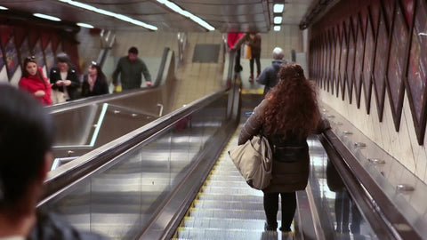 people riding escalator passing by woman in subway station - rear shot of lady heading downstairs 1080 HD in NYC