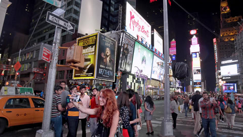 circling around pretty red head girl in Times Square in summer taking selfies at night