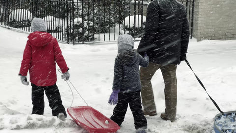father with children and sleds in snow going to Washington Square Park in winter blizzard snowing in New York City NYC