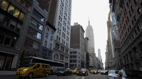 5th Ave traffic in early morning, cars and cabs driving with headlights on cloudy spring day in Manhattan with Empire State Building street view in 4K and 1080 HD in NYC