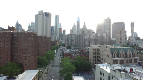 aerial view backing up from Manhattan skyscrapers to Chinatown buildings, cars on street downtown
