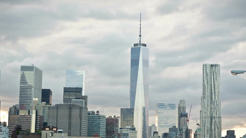 Freedom Tower view from Brooklyn Bridge in early evening, cars in traffic and tourists crossing pedestrian path in NYC