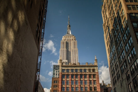Empire State Building view from between two buildings in alley on bright sunny day