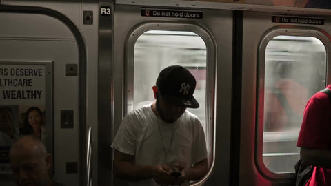 kid with Yankee cap riding subway with passing train in window in New York City