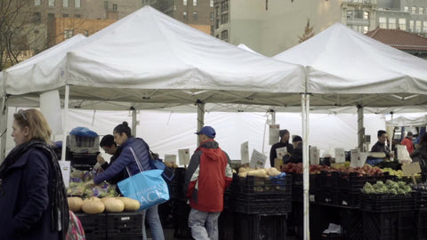 Union Square Park Farmers Market in winter with people buying and selling produce and food under tents