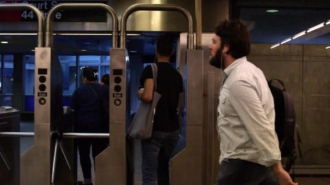 people walking in subway station, passing turnstiles in slow motion