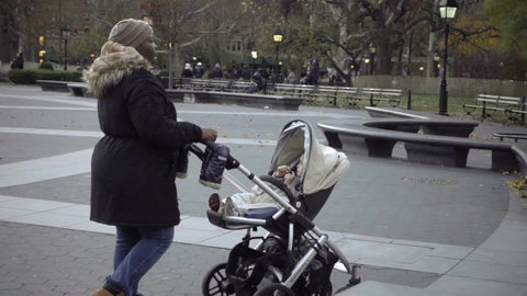 woman pushing stroller in Washington Square Park - black lady and white baby in winter