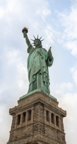 Statue of Liberty full view head to toe with base over blue sky and clouds during day