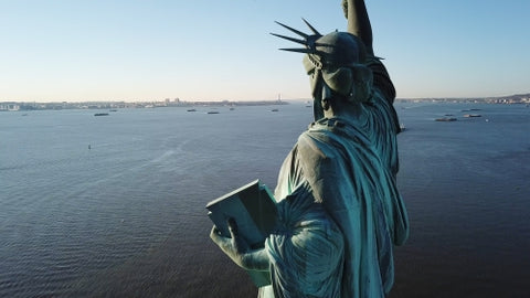 Statue of Liberty facing open harbor in New York City - aerial in water