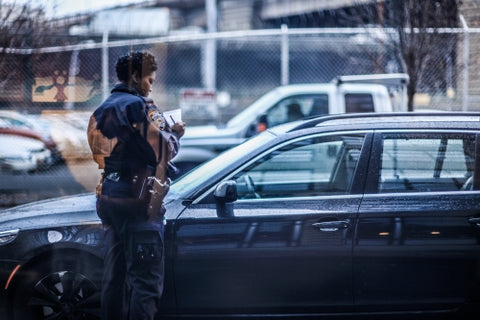 police officer writing parking ticket on street - female cop