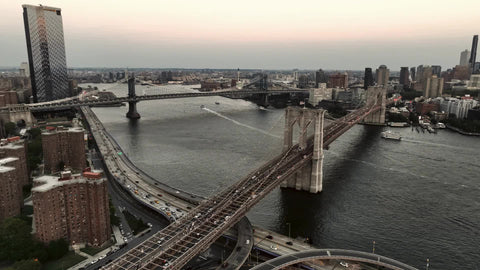aerial flying over half staff American flag Brooklyn Bridge Two Bridges East River New York City