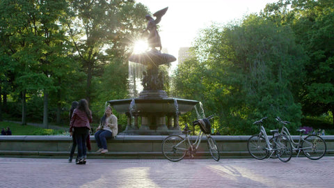 girls hanging out in Central Park by Bethesda statue with bicycles parked, leaning on circle