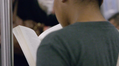 woman reading book on subway train