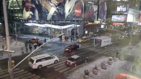 snowing on cars in traffic on 42nd street and 8th Ave off Times Square at night - high view through window