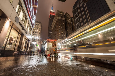 towering landmark Empire State Building from 34th st street view with streaking light from blur motion cars in traffic at night in Manhattan