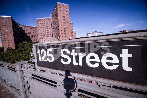 125th street subway sign in Harlem with housing projects in background in Uptown Manhattan NYC