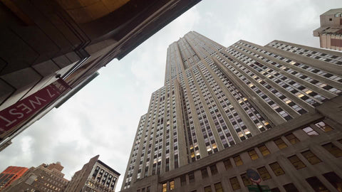 upward view of Empire State Building towering overhead - panning sky in NYC