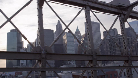 view of Manhattan skyline from inside Brooklyn Bridge, driving across landmark in NYC