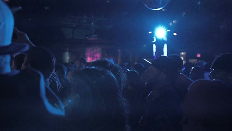 zooming in on crowd at rap show under bright lights