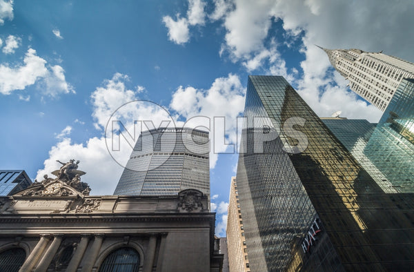 Grand Central Station Terminal with MetLife Building and Chrysler skyscraper towering over Midtown Manhattan on beautiful day - blue sky and clouds