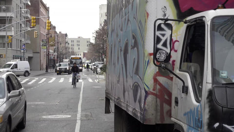man on bicycle riding past gritty graffiti truck in morning in NYC