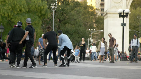 breakdancer doing windmills in circle of hip hop dancers in summer in Washington Square Park in NYC