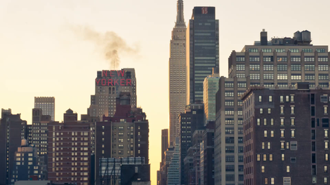 slow zoom out from Empire State Building and construction site with crane at sunset in Midtown Manhattan - 4K timelapse with cars driving in NYC