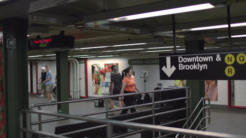 woman playing violin in subway station with Downtown and Brooklyn sign in NYC