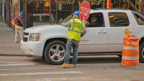 traffic control construction worker holding stop sign giving directions to driver NYC