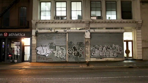 graffiti on store gate at night with cars and taxi cabs driving by in NYC - with audio