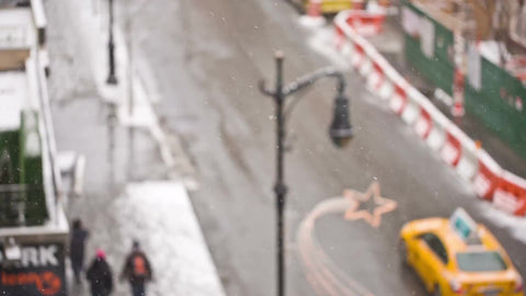 taxi cabs driving down winter street - bus in snow - people walking - snowing on holidays - overhead view