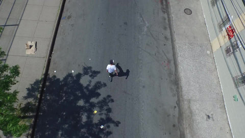 aerial of skater in Brooklyn skating down street on summer day in NYC