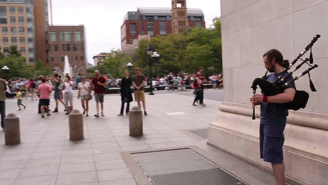 street musician playing bagpipes in Washington Square Park on summer day in NYC