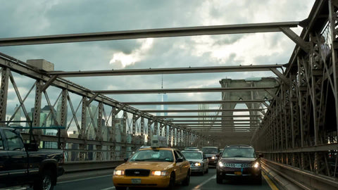 taxi cab crossing Brooklyn Bridge - cars driving in traffic on cloudy day in NYC