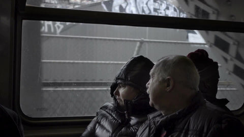 old couple looking out window from elevated subway train in winter, NYC