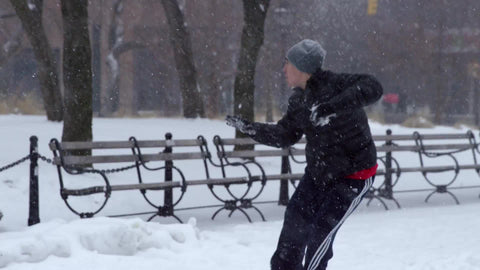 young man getting hit with snowballs in snow ball fight Washington Square Park winter blizzard - snowing in NYC