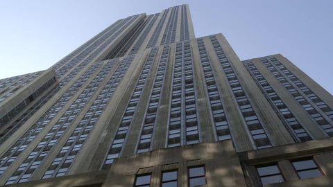 upward angle of Empire State Building towering over street reaching to sky in NYC