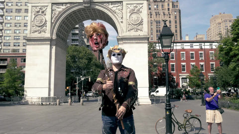 anti-Trump activist in costume mask with decapitated head - beheaded on stick in Washington Square Park New York City