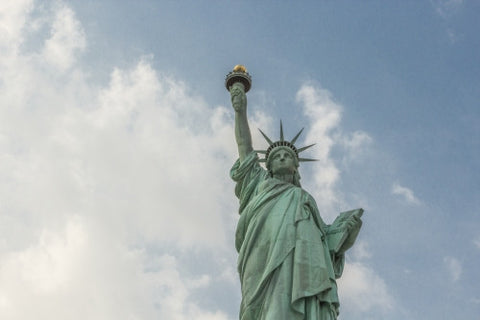 Statue of Liberty - medium shot from waist up over blue sky with clouds on bright day