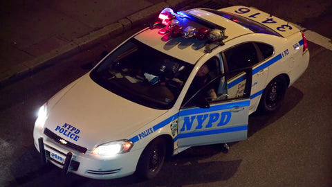 police from overhead view - officer getting out of NYPD car with flashing turret lights in street at night