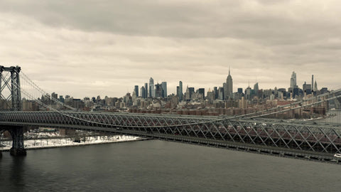 aerial pulling back from Williamsburg Bridge and Empire State Building lateral tracking aerial drone shot with Manhattan skyline over East River New York City NYC