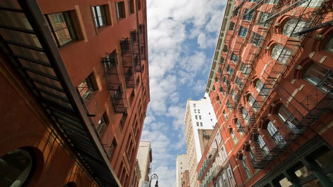 SoHo buildings and cobblestone street in summer - tilting down to cars