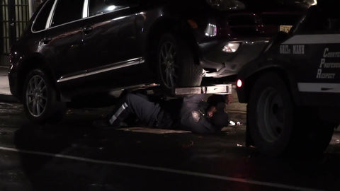 tow truck officer underneath car at night