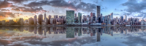 wide panoramic view of Manhattan skyline across East River with reflection of skyscrapers at sunset in NYC
