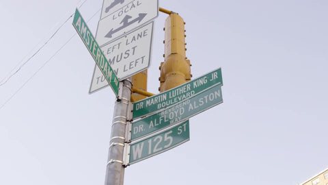 125th St and Amsterdam street sign tilting down to chicken and pizza store in Harlem NYC