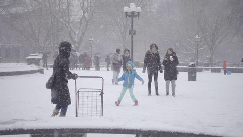mother and father throwing snowballs at daughter in winter blizzard snowing in NYC