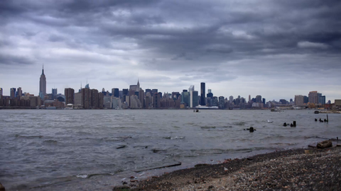 cloudy gloomy beach view of Manhattan skyline from across water with Empire State Building